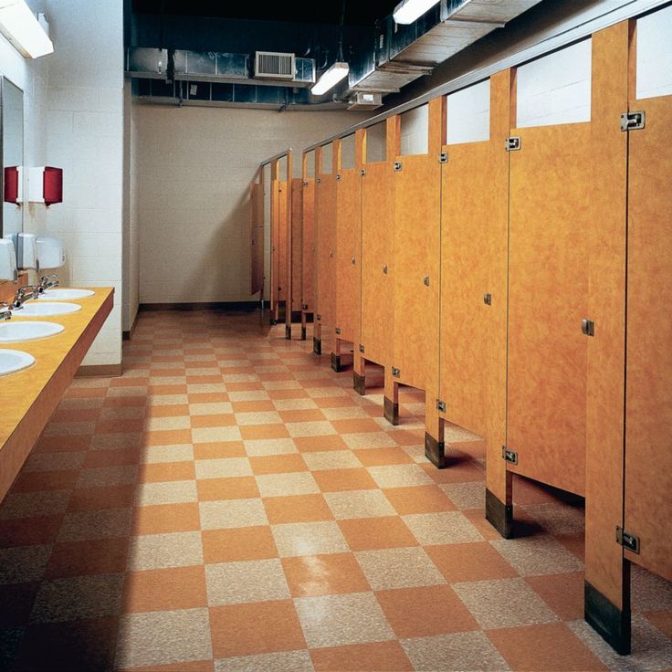 a row of urinals in a bathroom with checkered flooring and orange walls