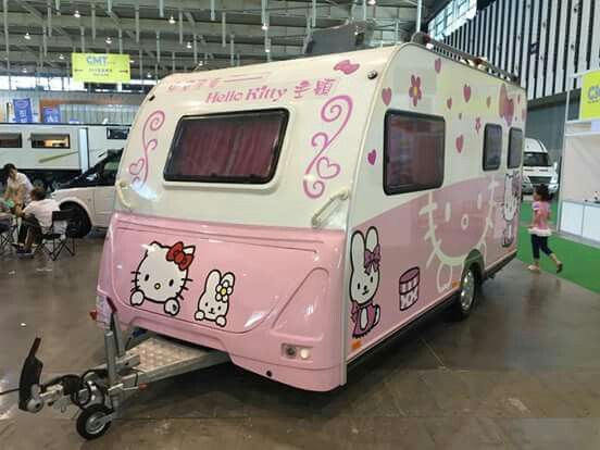 a pink and white trailer with hello kitty decals on it's side at an indoor event