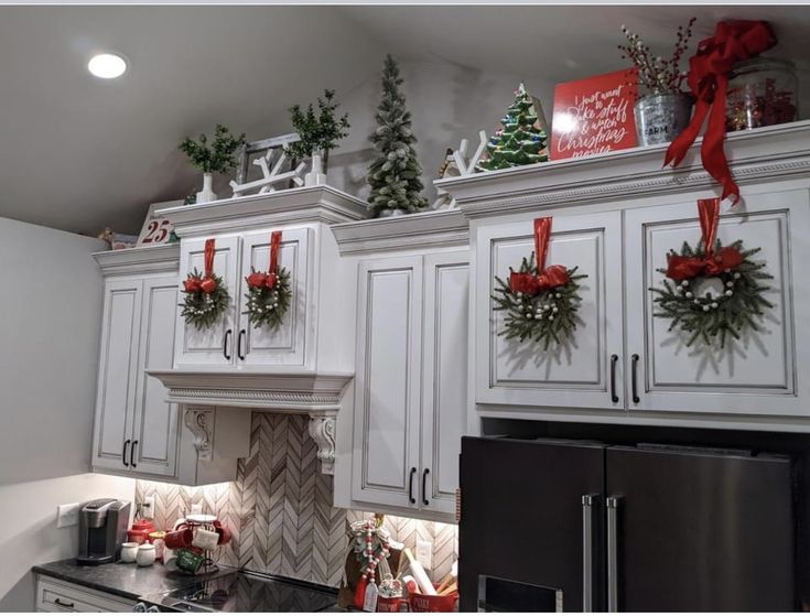 a kitchen decorated for christmas with wreaths on the cabinets and decorations hanging from the ceiling