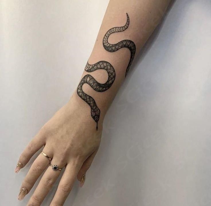 a woman's hand with a black snake tattoo on the left arm and wrist