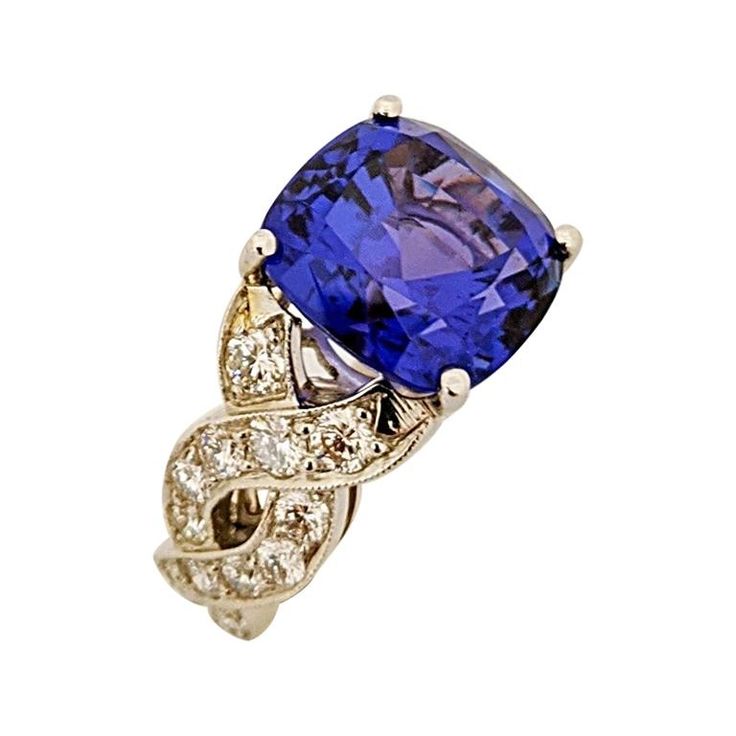 This one of a kind piece created by Cellini Jewelers NYC, features a handmade Platinum setting which surrounds an intense cushion cut Tanzanite. This very vibrant stone is set in a four prong setting with Diamond braiding down the sides . Finger size 6 Sizing options may be available Total Tanzanite Weight 9.65 carats Total Diamond Weight 1.24 carats Stamped PT900 with the jewelers hallmark Tanzanite Rings, Sapphire Cocktail Ring, Diamond Ring Princess Cut, Tanzanite Diamond Ring, Tanzanite Diamond, American Modern, Tanzanite Ring, Diamond Cocktail Rings, Diamond Settings