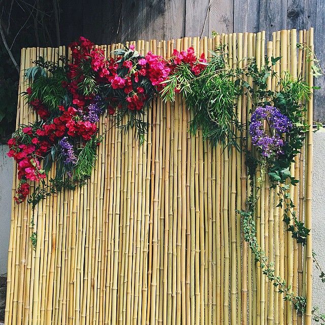 a bamboo mat with flowers on it and greenery growing up the side of it