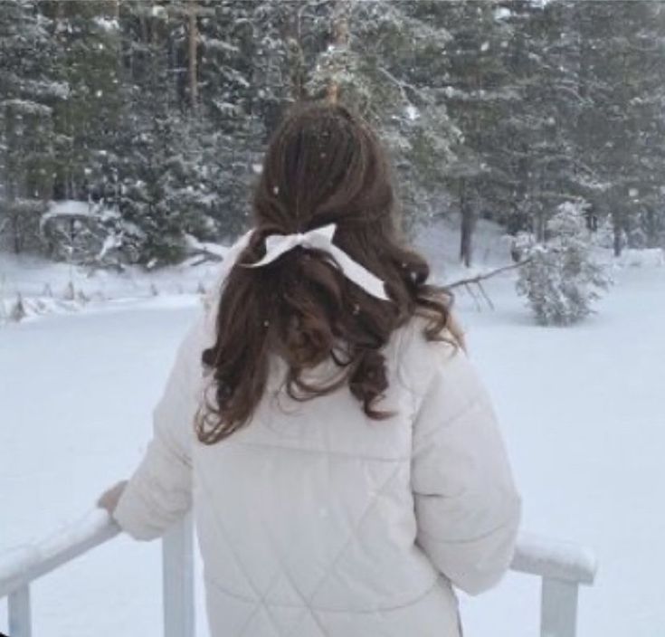 a woman standing on top of a snow covered slope next to a tree filled forest