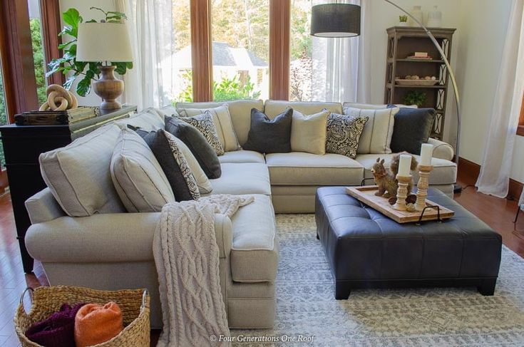 a living room filled with lots of furniture next to a window covered in white curtains