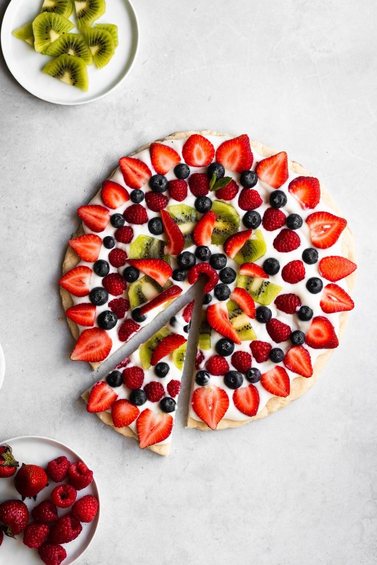 a fruit pizza with kiwis, strawberries and kiwi slices on plates