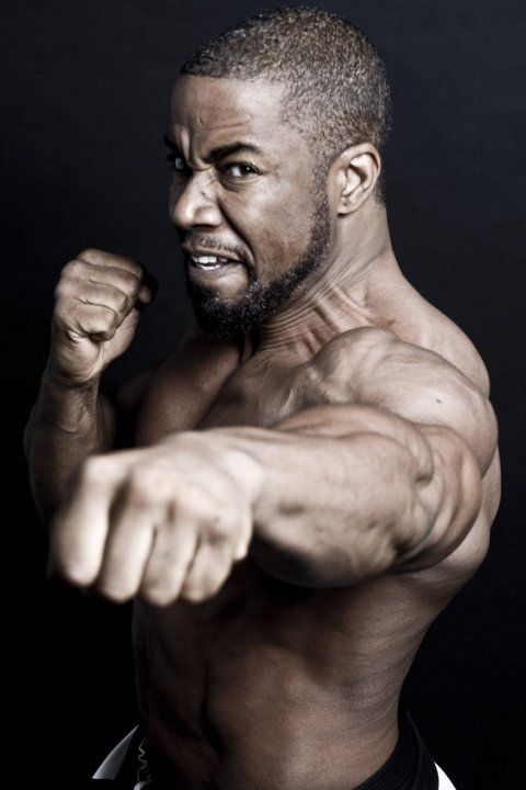 a man flexing his muscles in front of a black background