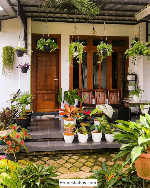 the front porch is filled with potted plants and hanging planters, along with other houseplants