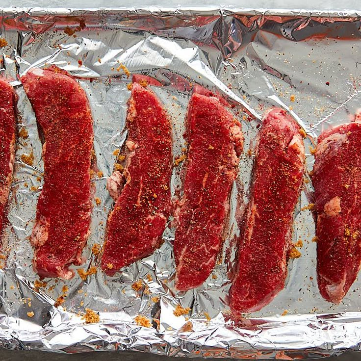 four pieces of raw meat on tin foil