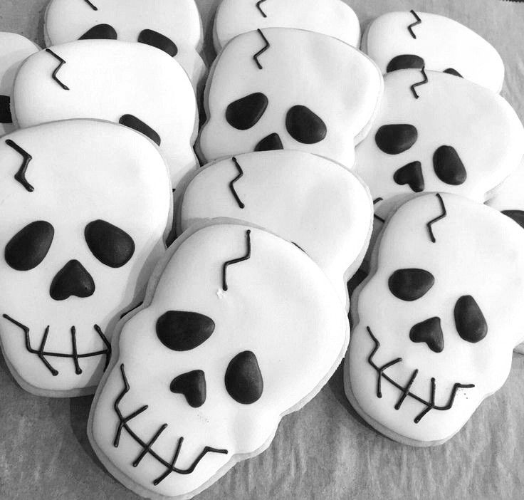 decorated cookies with black and white icing in the shape of skulls