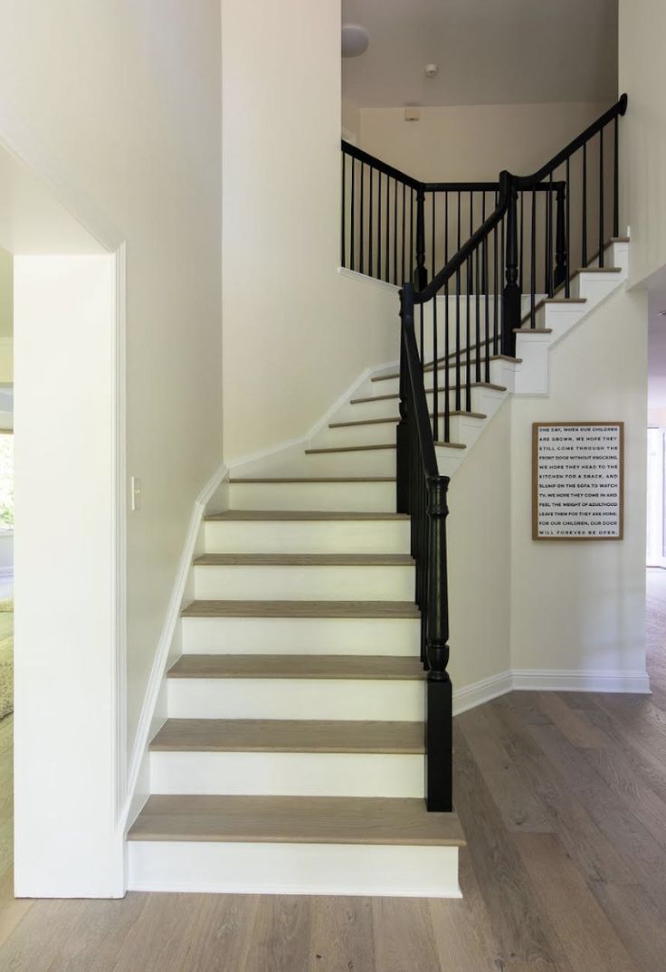 a white staircase with black railing and wood flooring in a home's entryway