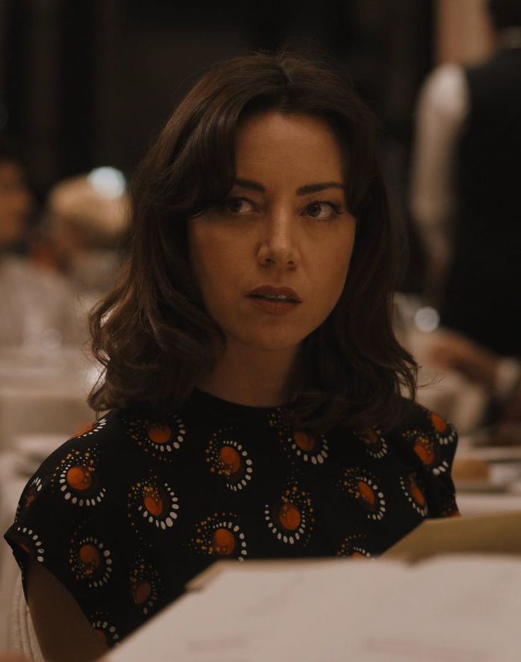 a woman sitting at a table with papers in front of her and looking off to the side