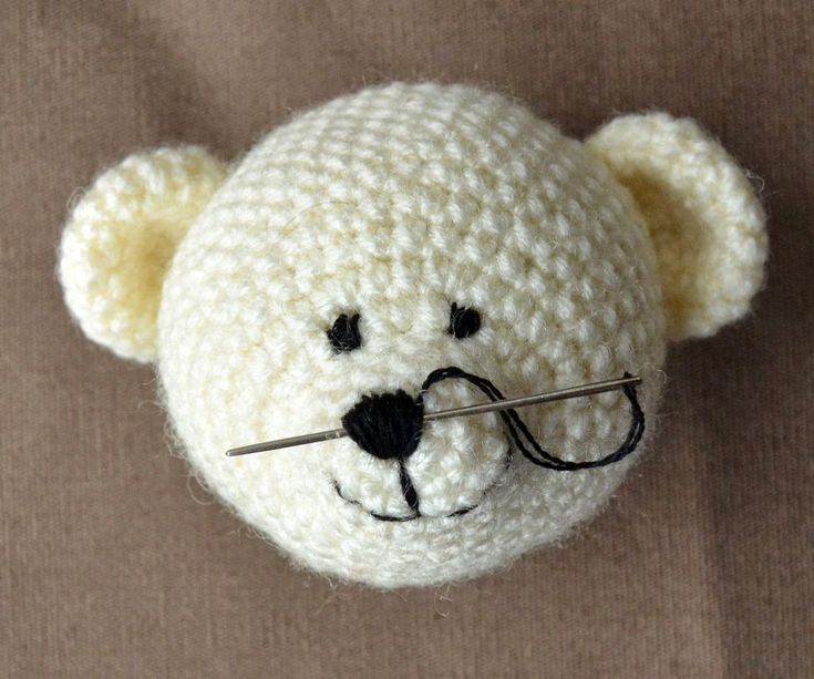 a crocheted teddy bear with a needle in it's mouth and nose