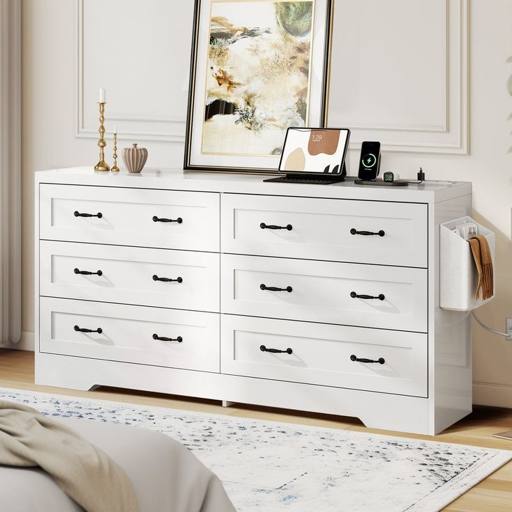 there is a white dresser with many drawers in the room next to a painting on the wall