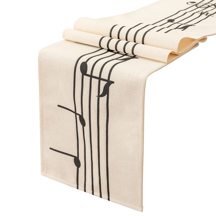 the table runner is decorated with musical notes and black ink on white linen, along with two folded napkins