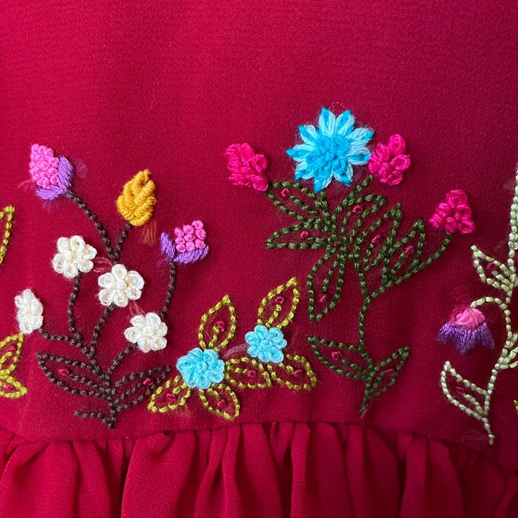 a red dress with colorful flowers on the front and back, along with beads in the middle