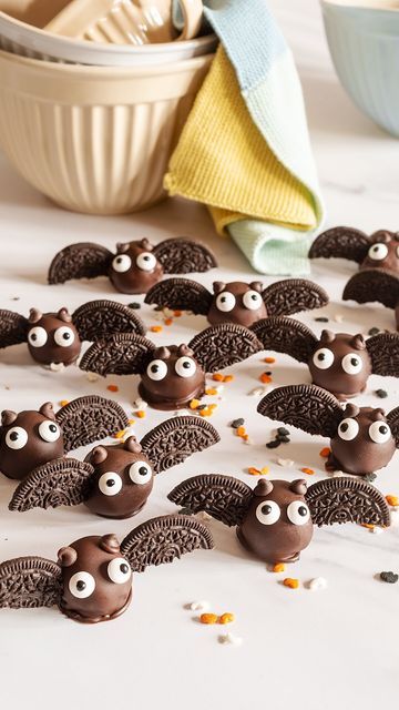 chocolate bats with googly eyes are on the table next to a bowl of cereal