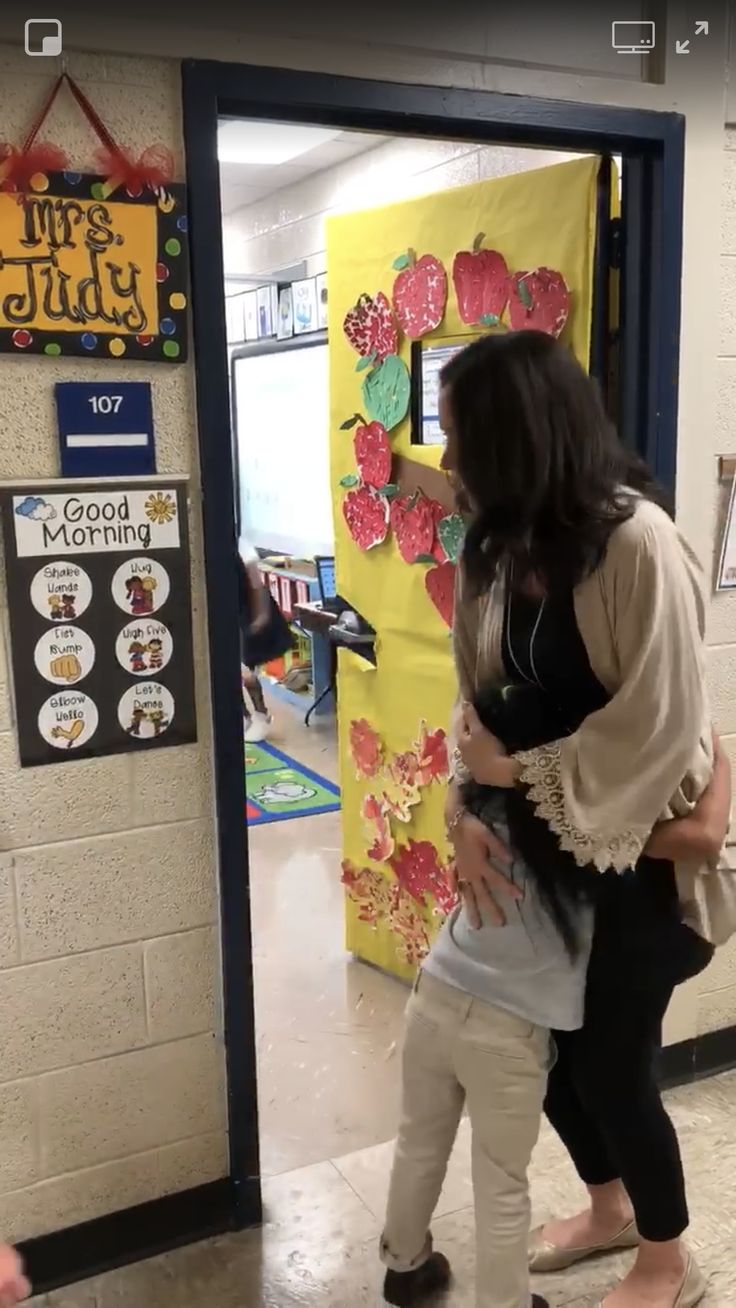 two girls are hugging each other in front of a door decorated with flowers and hearts