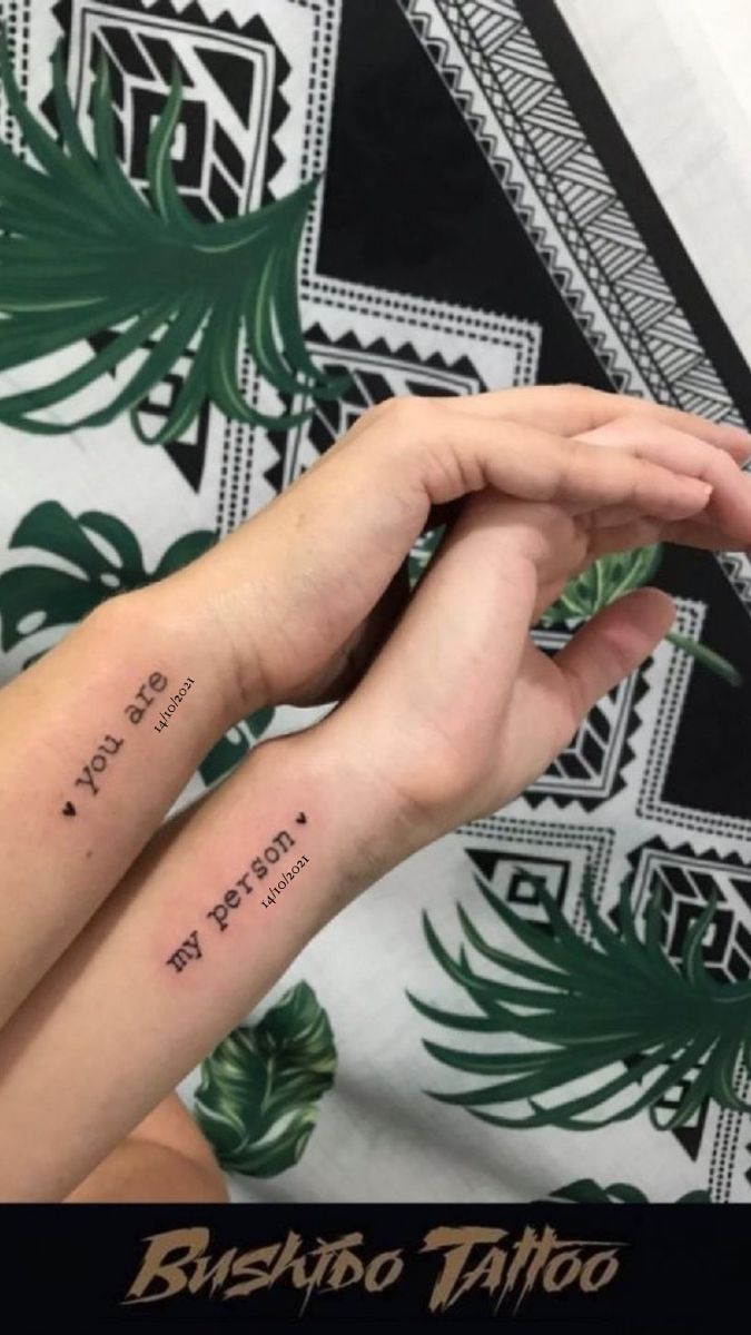 two people with matching tattoos on their arms, one is holding the other's hand