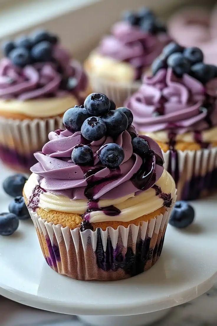 blueberry cupcakes with purple frosting on a white plate