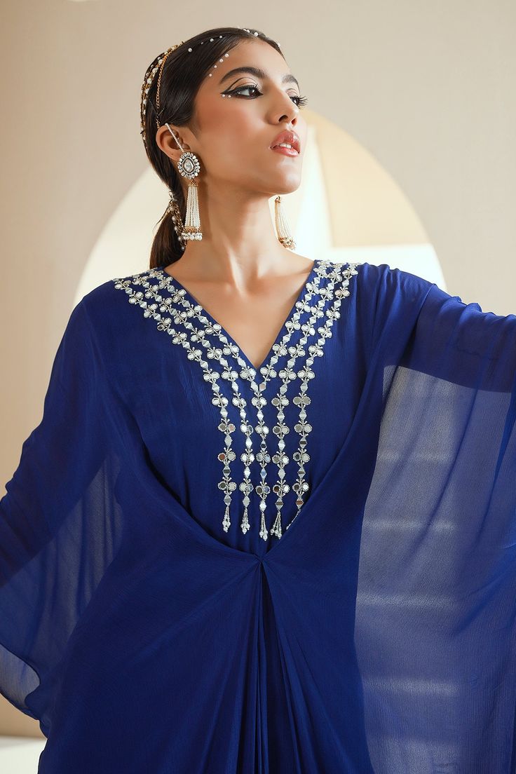 Electric blue kaftan with hand embroidered neckline with zari, mirror, glass beads and white beads.
Components:1
Pattern:Hand Embroidered
Type of Work:Floral Motifs
Neckline:V-Neck
Sleeve Type:Flared Sleeves
Fabric:Chiffon, Lining: Satin
Color:Blue
Other Details:
Front drapes
Note: The hair accessory worn by the model is not for sale
Occasion:Mehendi and Haldi - Aza Fashions Festive V-neck Kurta For Party, Traditional Mirror Work Kaftan For Party, Traditional Party Kaftan With Mirror Work, Bollywood Style V-neck Party Kaftan, Elegant V-neck Dress For Navratri, Party Georgette Kaftan In Maxi Length, Party Georgette Maxi Kaftan, Festive Kaftan With Mirror Work For Reception, Party Kaftan With Mirror Work For Festivals