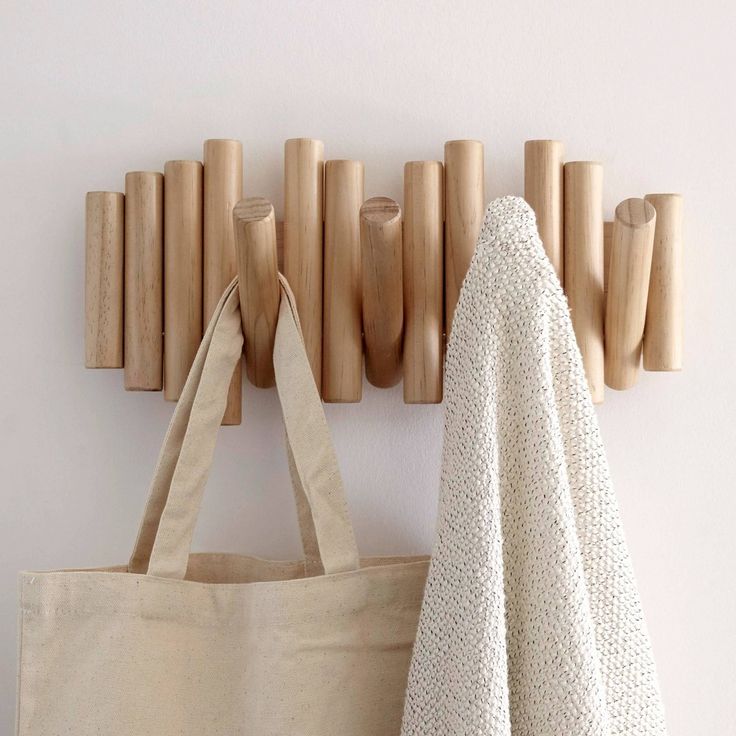 a tote bag hanging on the wall next to a coat rack with wooden pegs