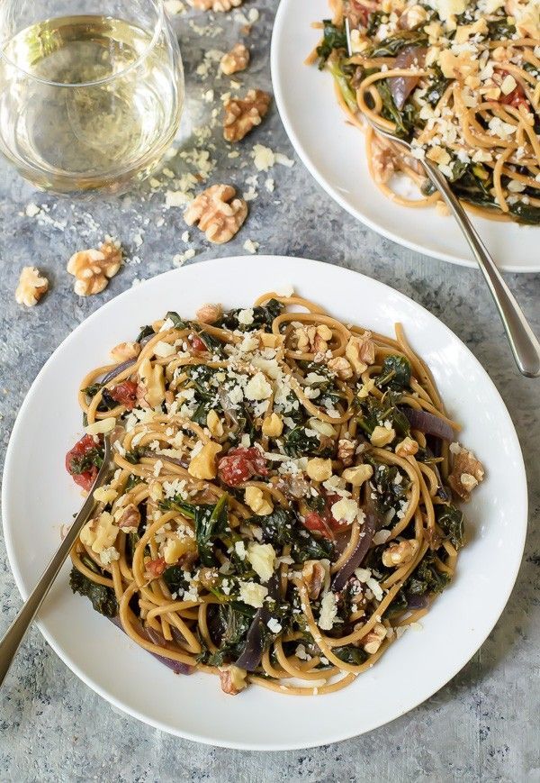 a white plate topped with pasta and spinach covered in fettuccine sauce