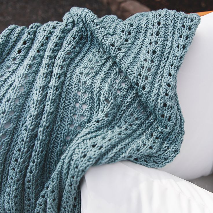 a knitted blanket sitting on top of a white couch