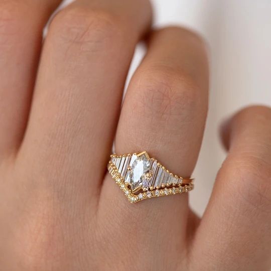 a woman's hand with a diamond ring on top of her finger and gold band