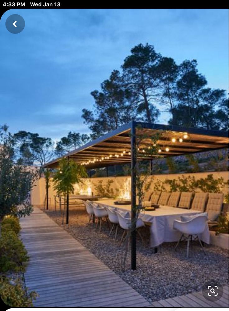 an outdoor dining area is lit up at night with lights on the tables and chairs