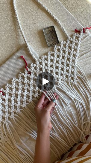 a woman is holding a piece of white yarn