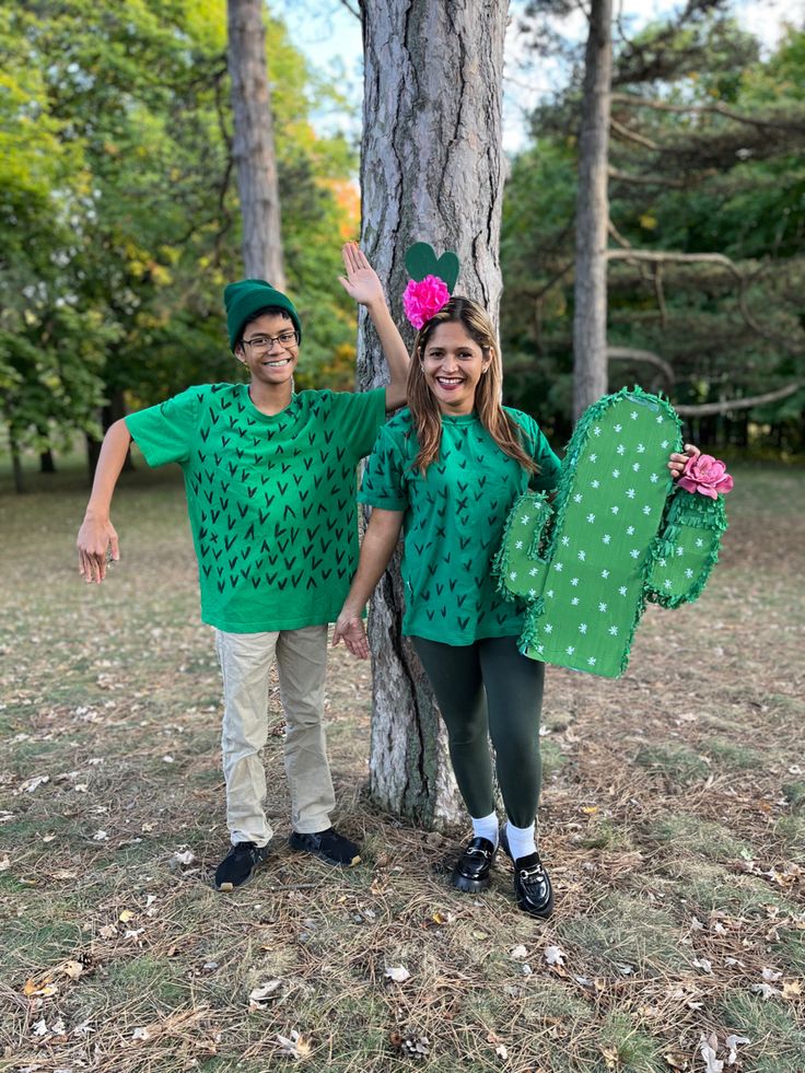 two people dressed in green standing next to a tree