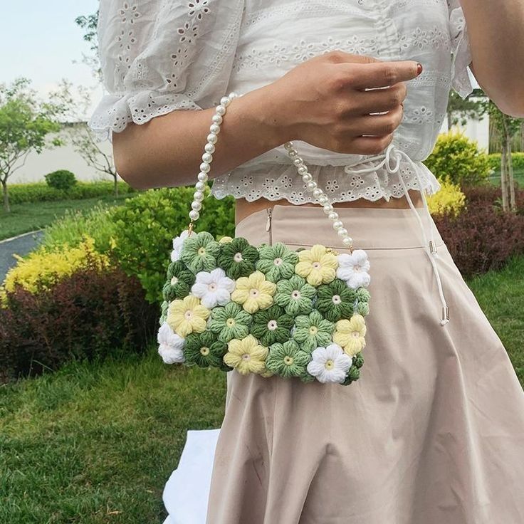 a woman holding a cell phone in her right hand while wearing a white top and beige skirt