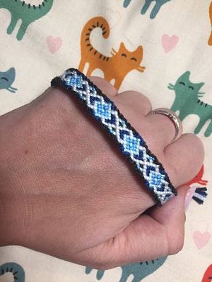 a person wearing a bracelet that has cats on it and is holding onto their hand