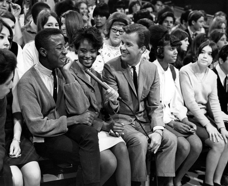 a group of people sitting next to each other in front of a crowd with a baseball bat