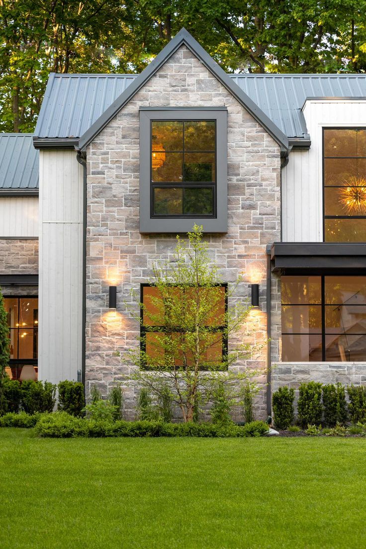 a brick house with two windows on the front and one window in the back that is lit up