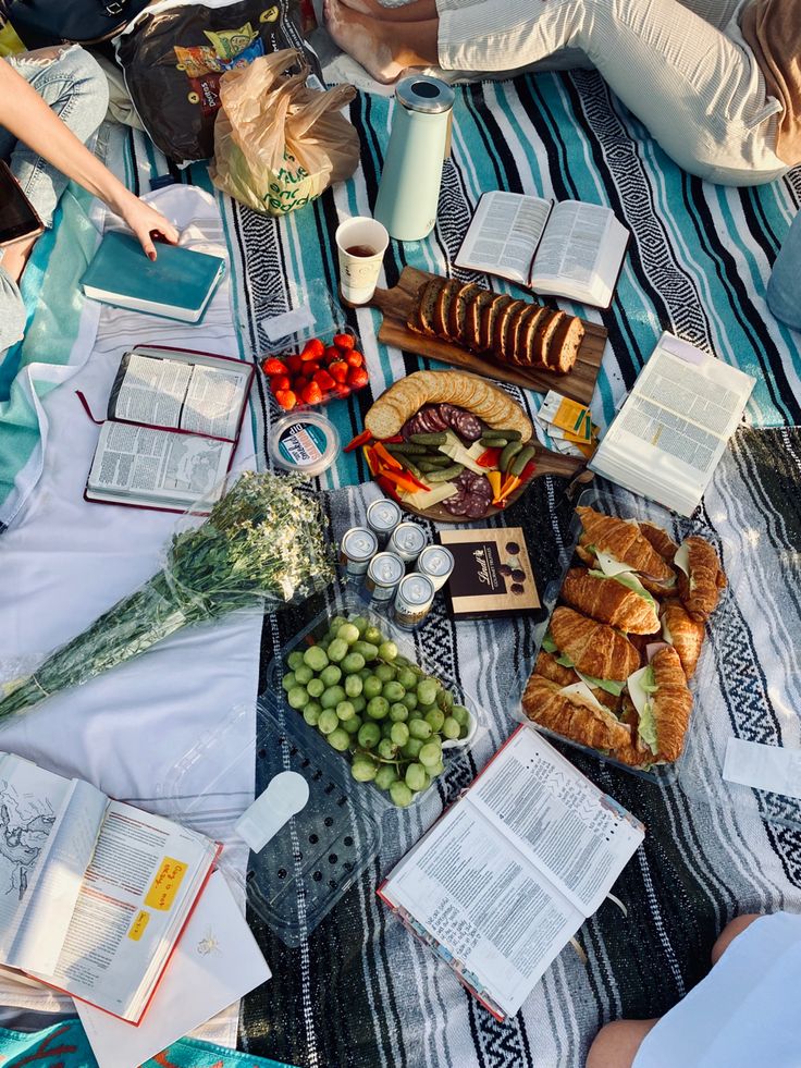 people are sitting at a table with food and books on it, including croissants