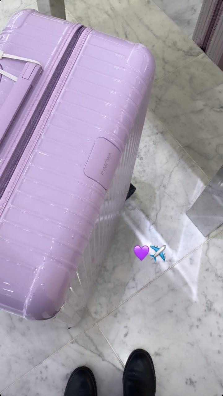 a purple piece of luggage sitting on top of a marble floor next to a pair of black shoes