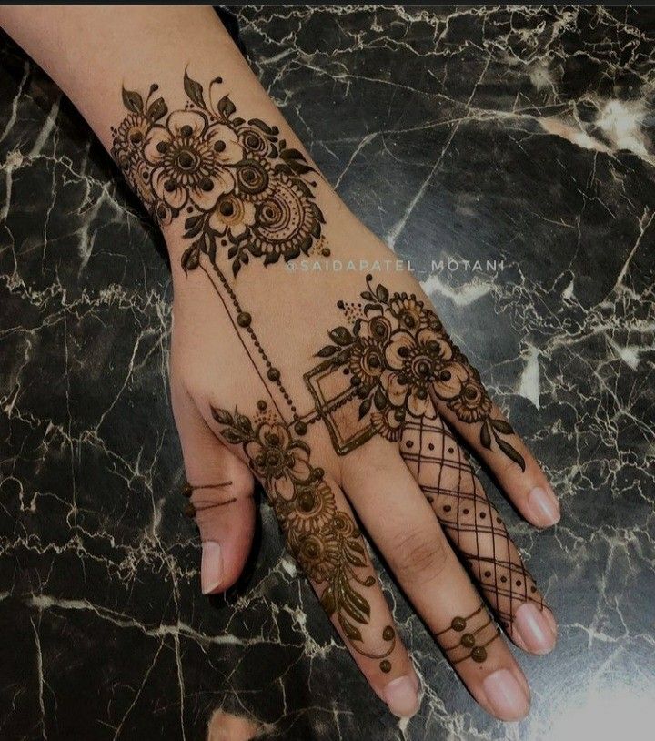 a woman's hand with henna tattoos on it, and an intricate design