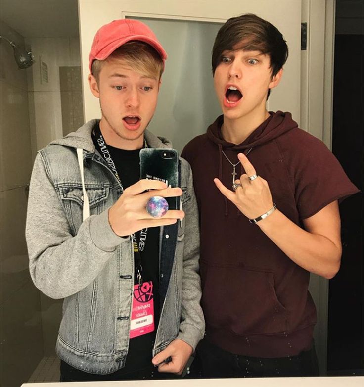 two young men standing next to each other in front of a mirror taking a selfie