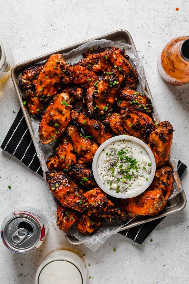 grilled chicken wings with ranch dressing on a tray next to two glasses of beer