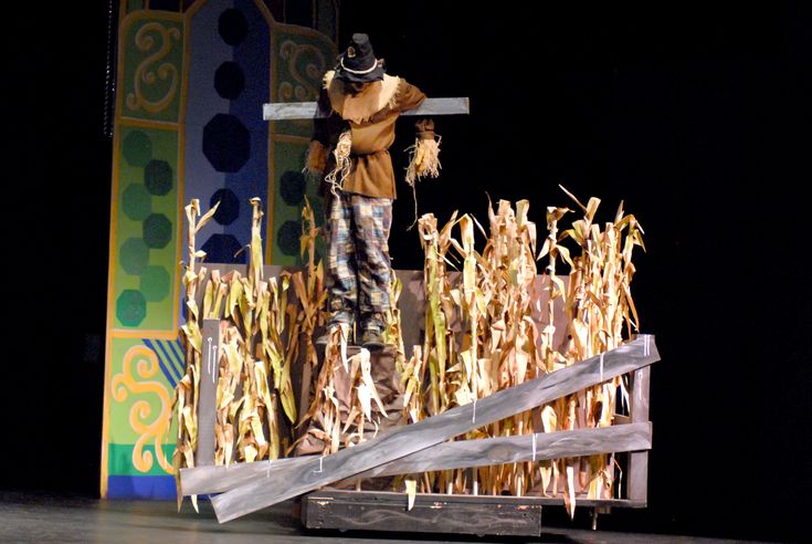 a man standing on top of a wooden crate next to a pile of dead corn