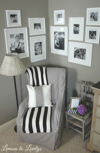 a gray chair with black and white striped pillows in front of pictures on the wall