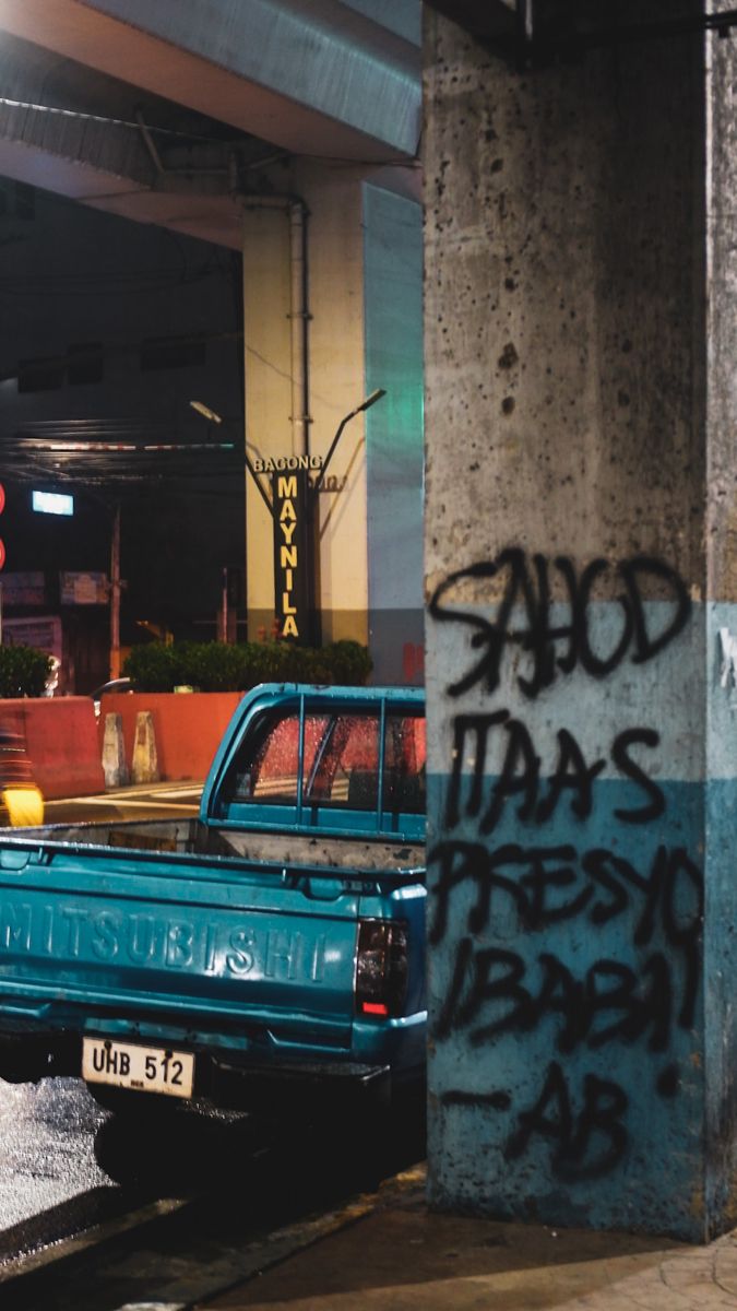 an old blue pickup truck parked on the side of the road with graffiti all over it