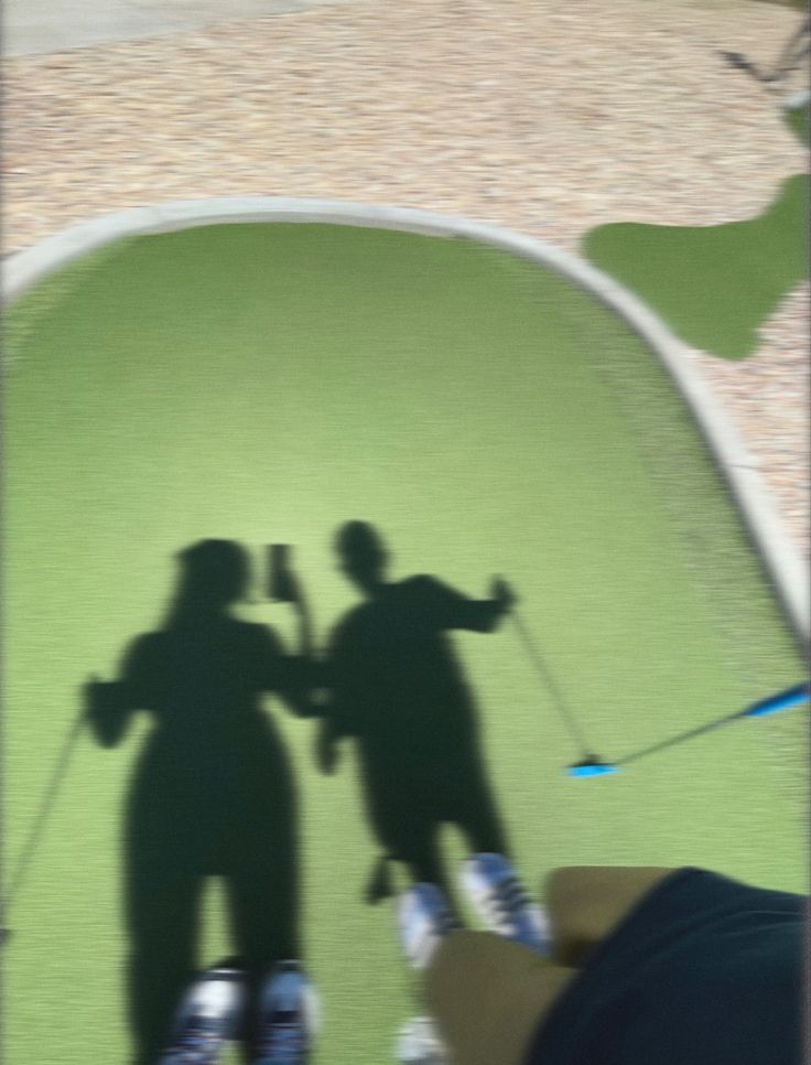 the shadow of two people holding golf clubs