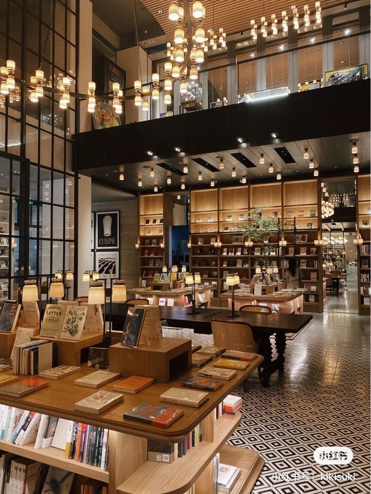 the inside of a bookstore with many books on tables and lamps hanging from the ceiling