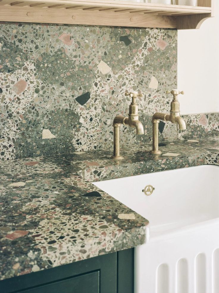 a white sink sitting under a faucet next to a counter top with two faucets