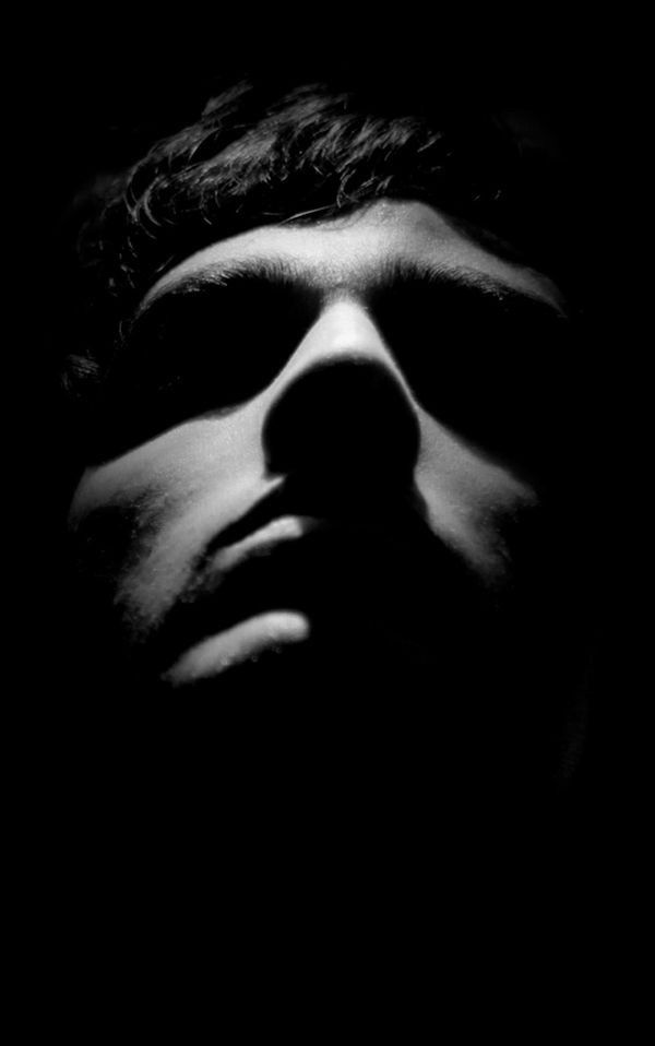 a black and white photo of a man's face with his eyes closed in the dark