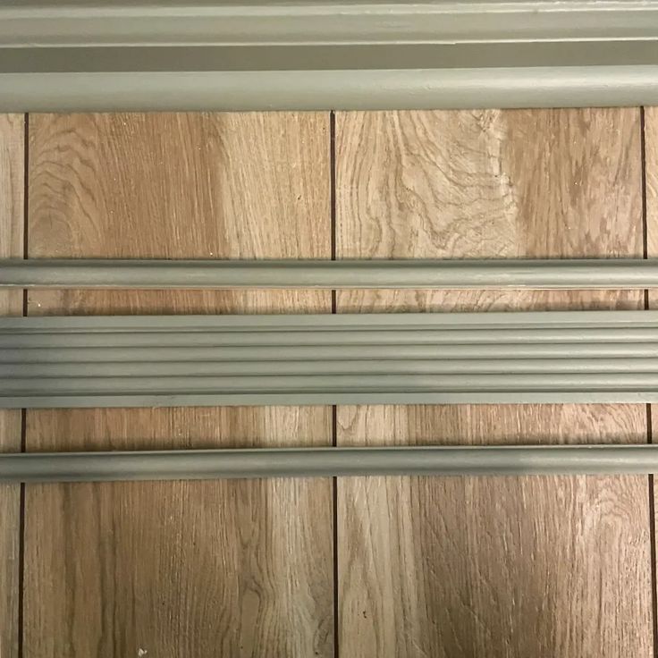 a close up of metal bars on a wooden door with wood flooring in the background