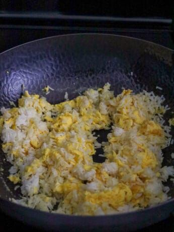 rice and eggs cooking in a pan on the stove