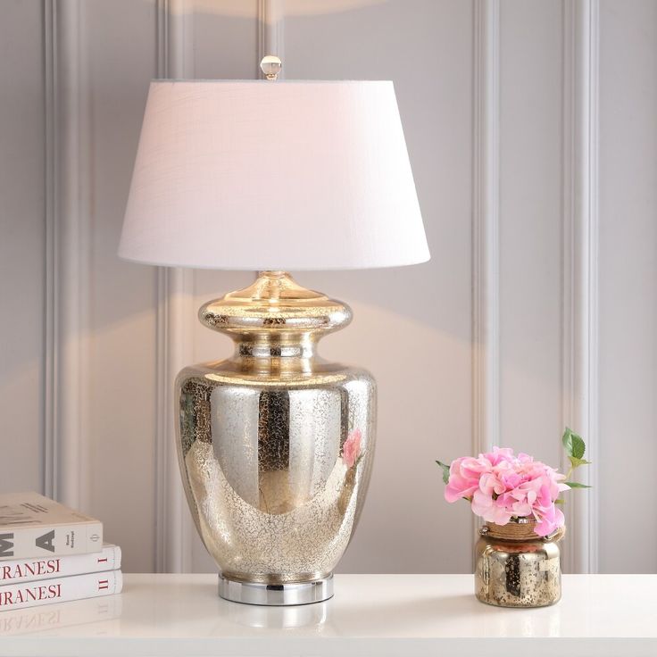 a lamp on a table next to a vase with flowers in it and two books